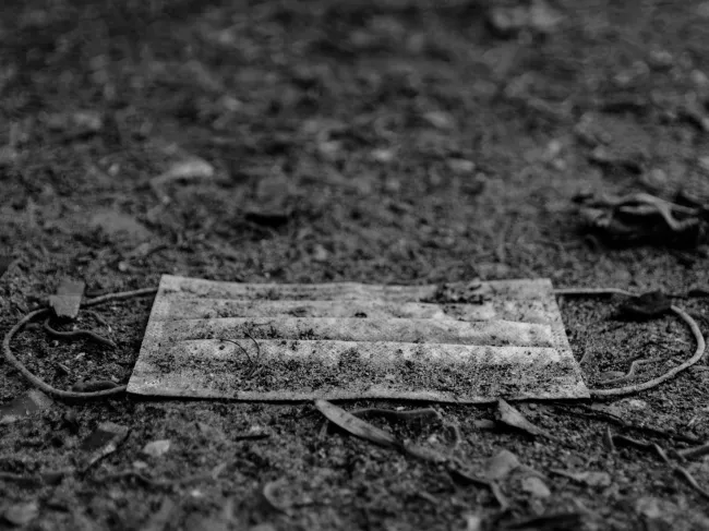 A covid mask lays discarded on the ground
